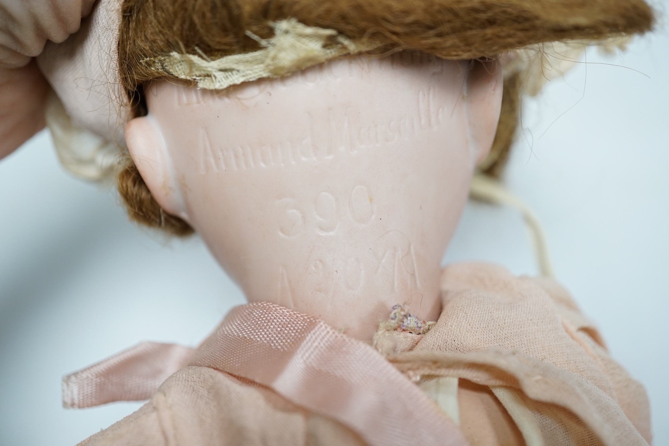 An AM390 bisque head doll, 63cm good condition, and an AM390, missing two fingers and wear on other hand, 58cm